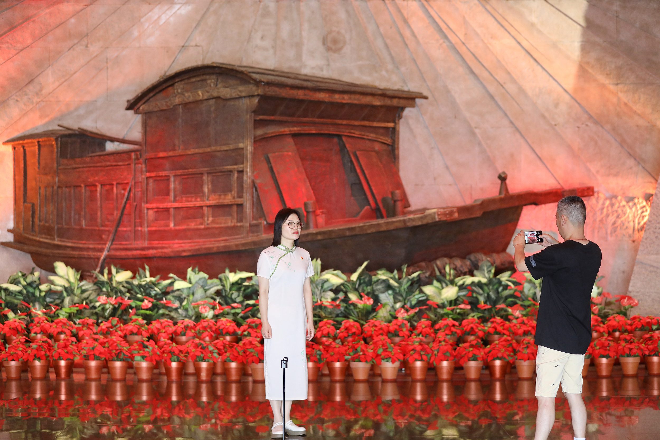 2025年6月24日，浙江嘉興，游客在南湖革命紀(jì)念館與紅船雕塑合影。（圖片來源：視覺中國）